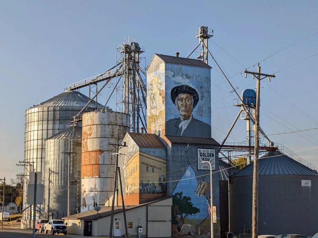 A small Minnesota town's grain elevators and painted silos beside utility poles and buildings