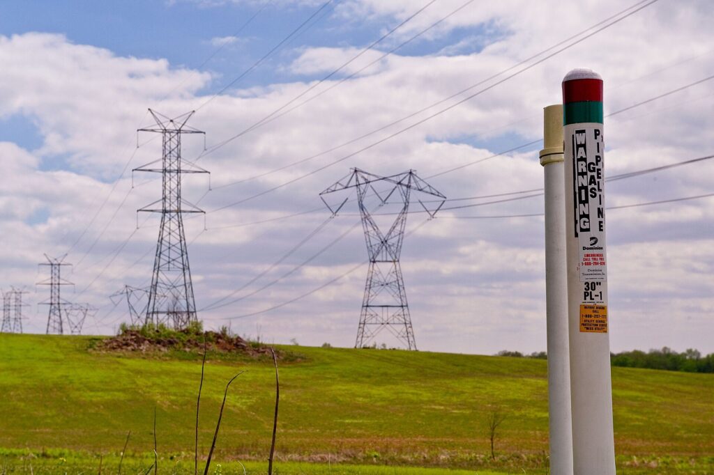 A pipeline marker post along a grassy right-of-way under open skies